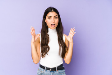 Young indian woman isolated on purple background celebrating a victory or success, he is surprised and shocked.