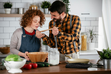 Boyfriend and girlfriend making delicious food at home. Loving couple cooking in kitchen.