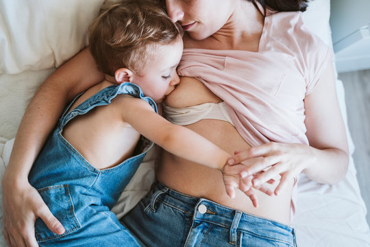 Mother breast feeding baby girl on bed