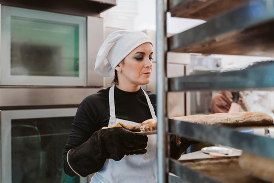 Female baker holding baking tray at bakery