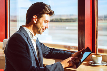 Young businessman using digital tablet at airport cafe