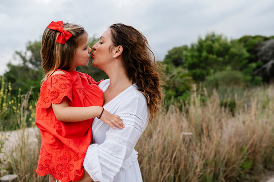 Affectionate mother and daughter kissing at countryside