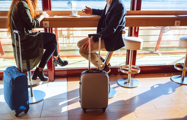 Business couple sitting with luggage at airport cafe