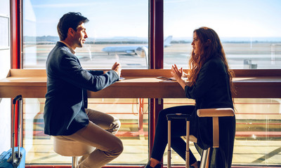 Business couple talking while sitting at airport cafe