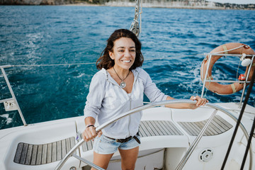 Smiling female sailor driving sailboat on sea