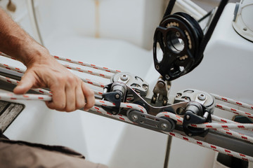 Hand of sailor maneuvering with mainsail in sailboat
