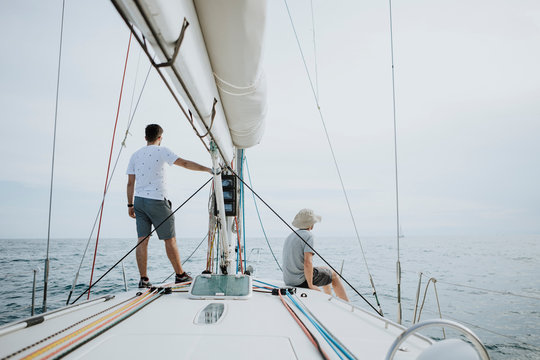 Friends looking at view while sailing on sailboat against sky