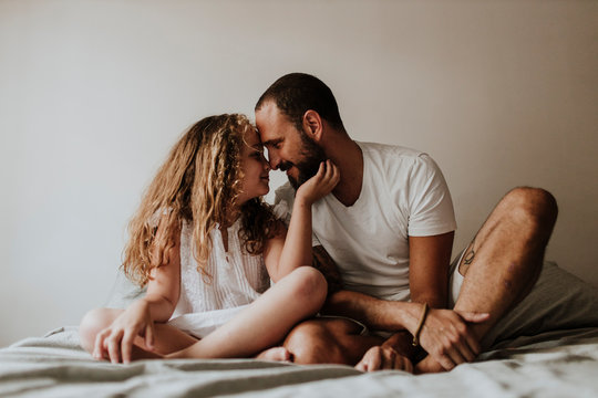 Father and daughter rubbing noses on bed at home