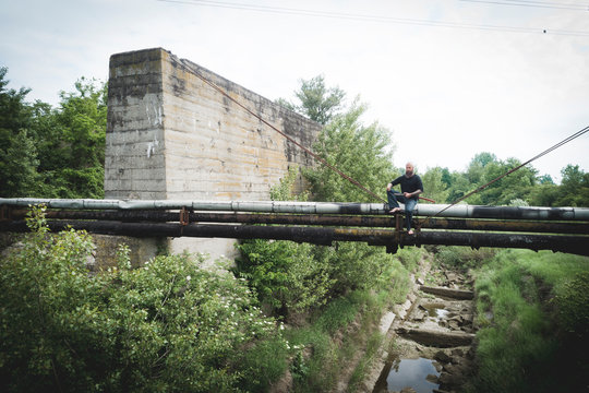 Drone shot of man with sword sitting on old pipes against sky