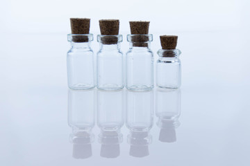 Empty small glass transparent flask bottles sealed with wooden stoppers. Objects are reflected on the surface as in a mirror. Macro