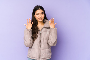 Young indian woman isolated on purple background showing number ten with hands.