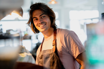 Smiling male owner looking away while working in coffee shop