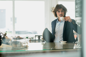 Businessman holding skateboard drinking coffee in restaurant