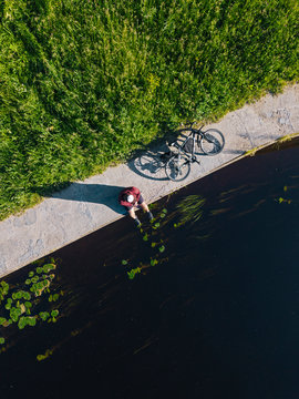 Aerial view of mid adult man with bicycle sitting at river coast