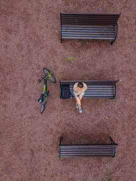 Aerial view of woman using smart phone while sitting on bench in park