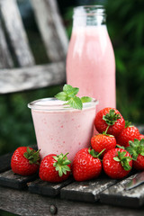 Glass of fresh strawberry shake, smoothie or milkshake and fresh strawberries on table. Healthy food and drink concept