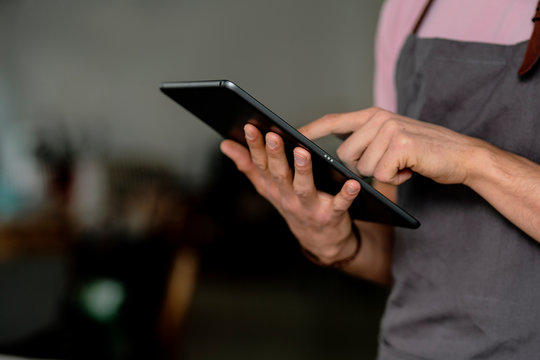 Close-up of male owner using digital tablet while standing in cafe