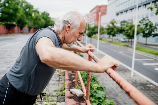 Senior man exercising on railing in city