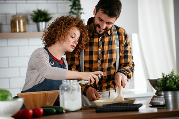 Boyfriend and girlfriend making delicious food at home. Loving couple cooking in kitchen.