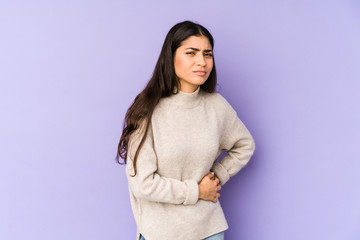 Young indian woman isolated on purple background having a liver pain, stomach ache.