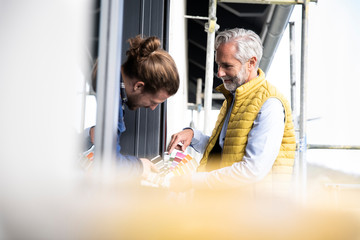 Architect and construction worker choosing color swatches at constructing house