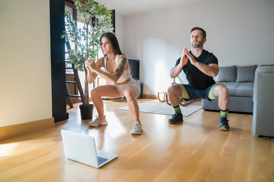 Couple exercising on hardwood floor at home