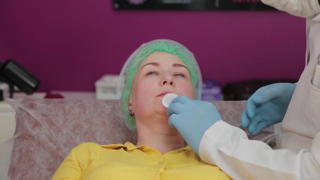 Beautiful woman rubbing lips before lip botox procedure.