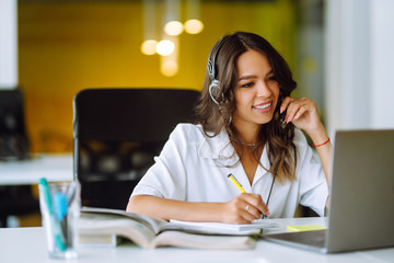 Distance learning. Young business woman, student, teacher, tutor wear wireless headset video conference calling on laptop computer talk by webcam.