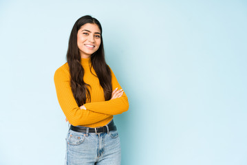 Young indian woman isolated on blue background who feels confident, crossing arms with determination.