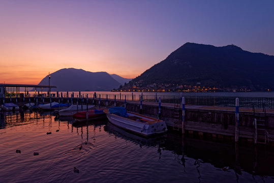 Italy, Lombardy, Sulzano, Boats and pier on lake Iseo at sunset