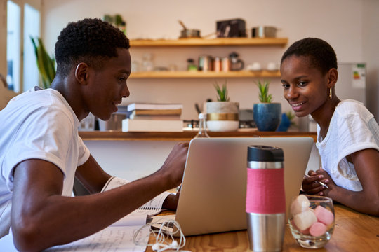 Smiling Couple Discussing Doubts Over Laptop While Studying At Home