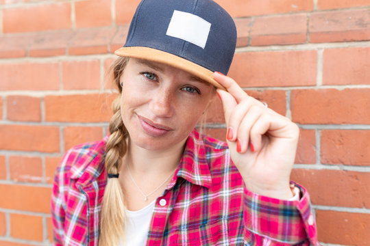 Close-up of woman with braided hair wearing cap against brick wall