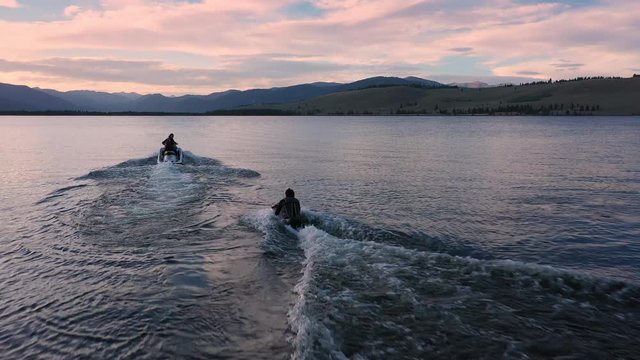  a watercraft pulling person up on the water as they kneeboard at Hebgen Lake during sunset.