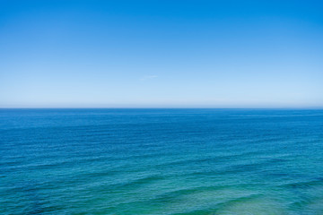 Obraz premium Beautiful blue green ocean seascape view with wave lines. Horizon line at sea and clear blue sky. Travel, vacation, holidays, relax feeling