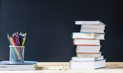 back to school concept pile of books against chalkboard