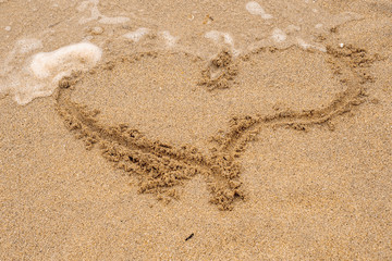 Heart shape sign being washed away by a wave.