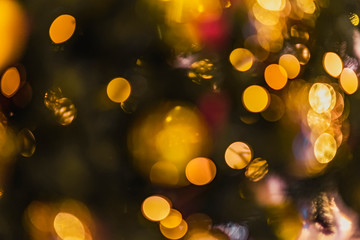 Abstract blurred christmas background with christmas tree decorated with shiny goden balls and illumination lights