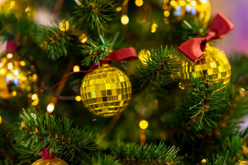 Fototapeta na wymiar Christmas tree with decorations, shiny golden balls, illumination light garlands. Abstract festive background for design. Selective focus.