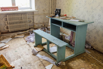 Room of an old abandoned building filled with trash on the floor and wooden desk