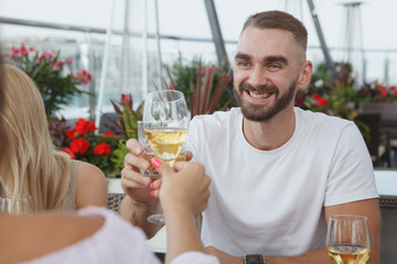 Handsome young man clinking glasses with his girlfriend while on a date at rooftop restaurant
