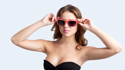 Close up portrait of pretty young woman in black stylish dress in sunglasses.