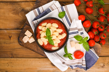 Fototapeta premium Homemade Italian Gnocchi with Red Sauce, Cheese with basil, olive oil . Close up. Home cooking. Traditional Italian cuisine from Rome and Sardinia. Above
