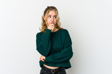 Young caucasian woman on white backrgound looking sideways with doubtful and skeptical expression.