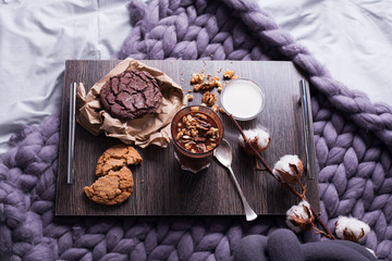 good morning - breakfast with sweet bun and tea on wooden tray and flowers in bed