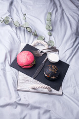 Colorful too mini burgers served on black plate as appetizer. Delicious classic, black and pink slider burgers loaded with beef patty, crispy chicken, lettuce, coleslaw, cheese, mushrooms. Image