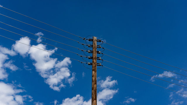 Minimalist pole with power lines with a blue sky background or a musical stave?