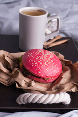 A huge burger on a serving board in a restaurant. In the background are fresh tomatoes, onions, lettuce, herbs and a mug of coffee. Selective focus, close up