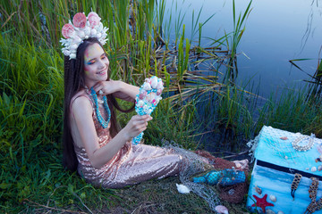 little mermaid in a crown of seashells trying on beads