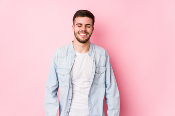 Fototapeta premium Young caucasian business man posing in a white background isolated laughs and closes eyes, feels relaxed and happy.< mixto >