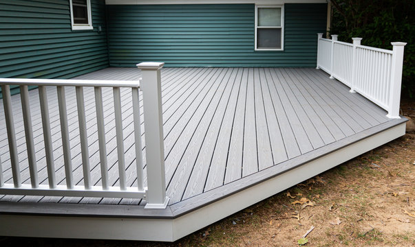 New composite deck on the back of a house with green vinyl siding.